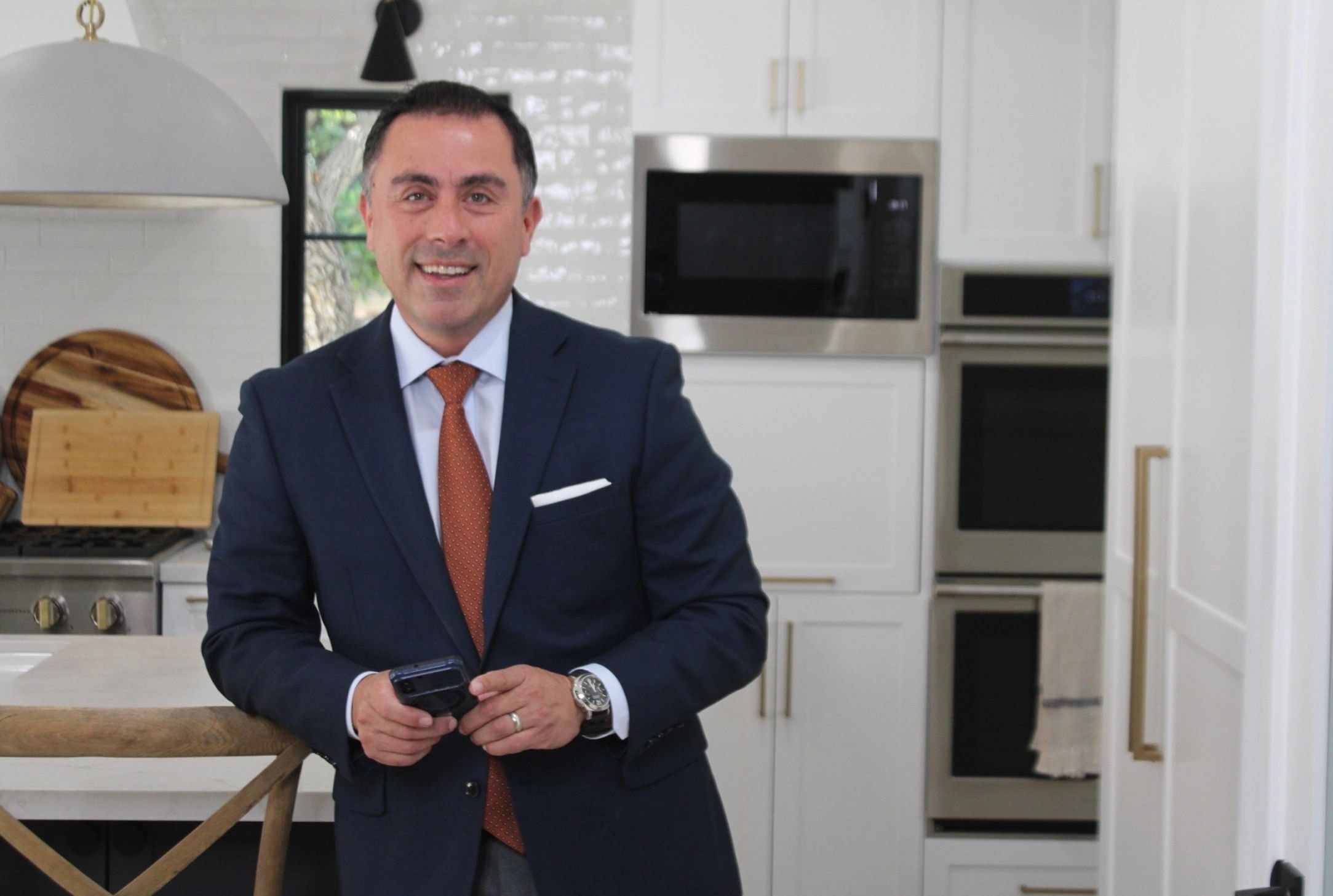 Carlos Escobar, real estate broker, standing in a modern kitchen